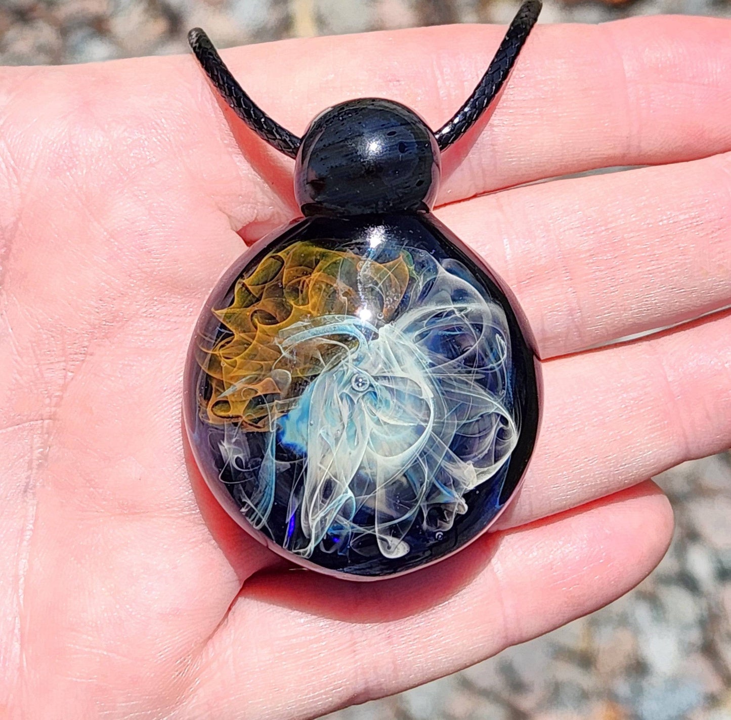 Front view of Gold & Silver Fumed Glass Pendant Necklace in hand. Handcrafted implosion pendant with vibrant cosmic swirl design.