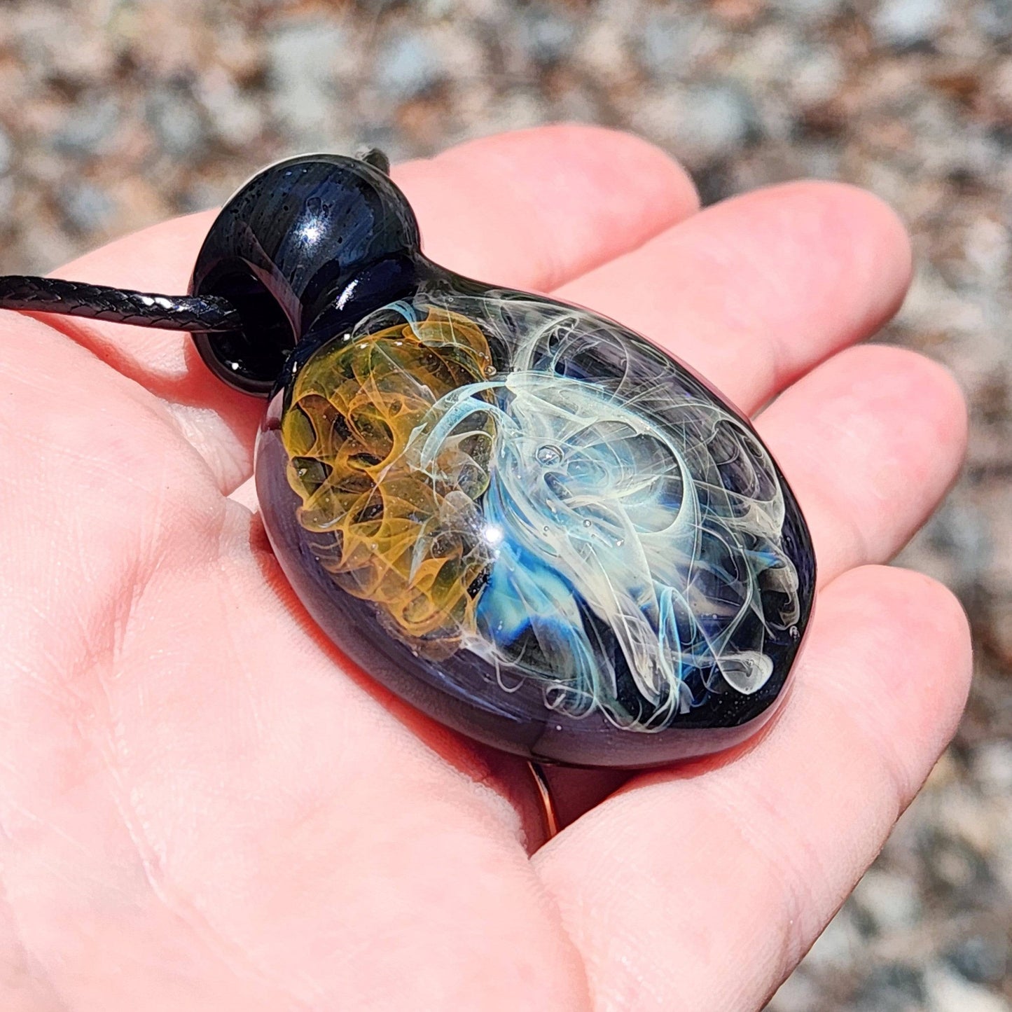 Gold & Silver Fumed Glass Pendant Necklace displayed in hand, showing scale and detail. Features swirling blue, gold, and silver glass art.