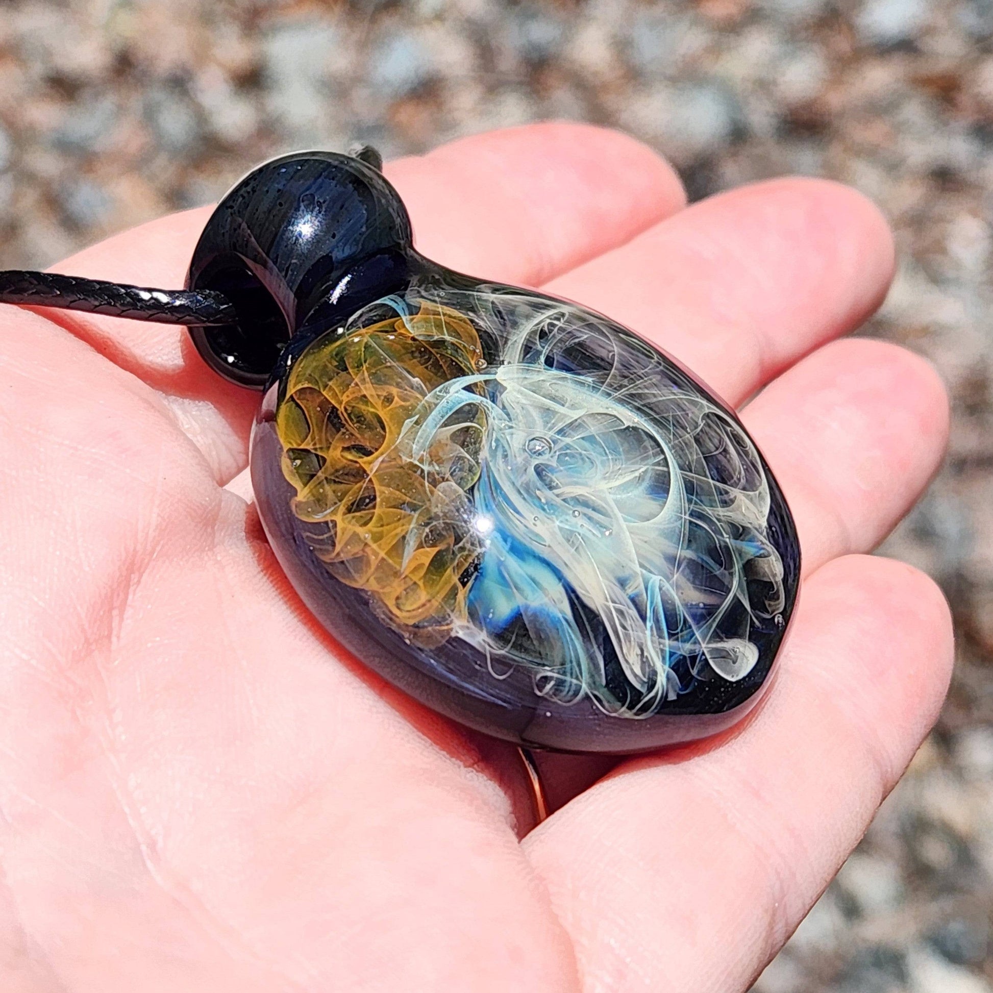 Gold & Silver Fumed Glass Pendant Necklace displayed in hand, showing scale and detail. Features swirling blue, gold, and silver glass art.