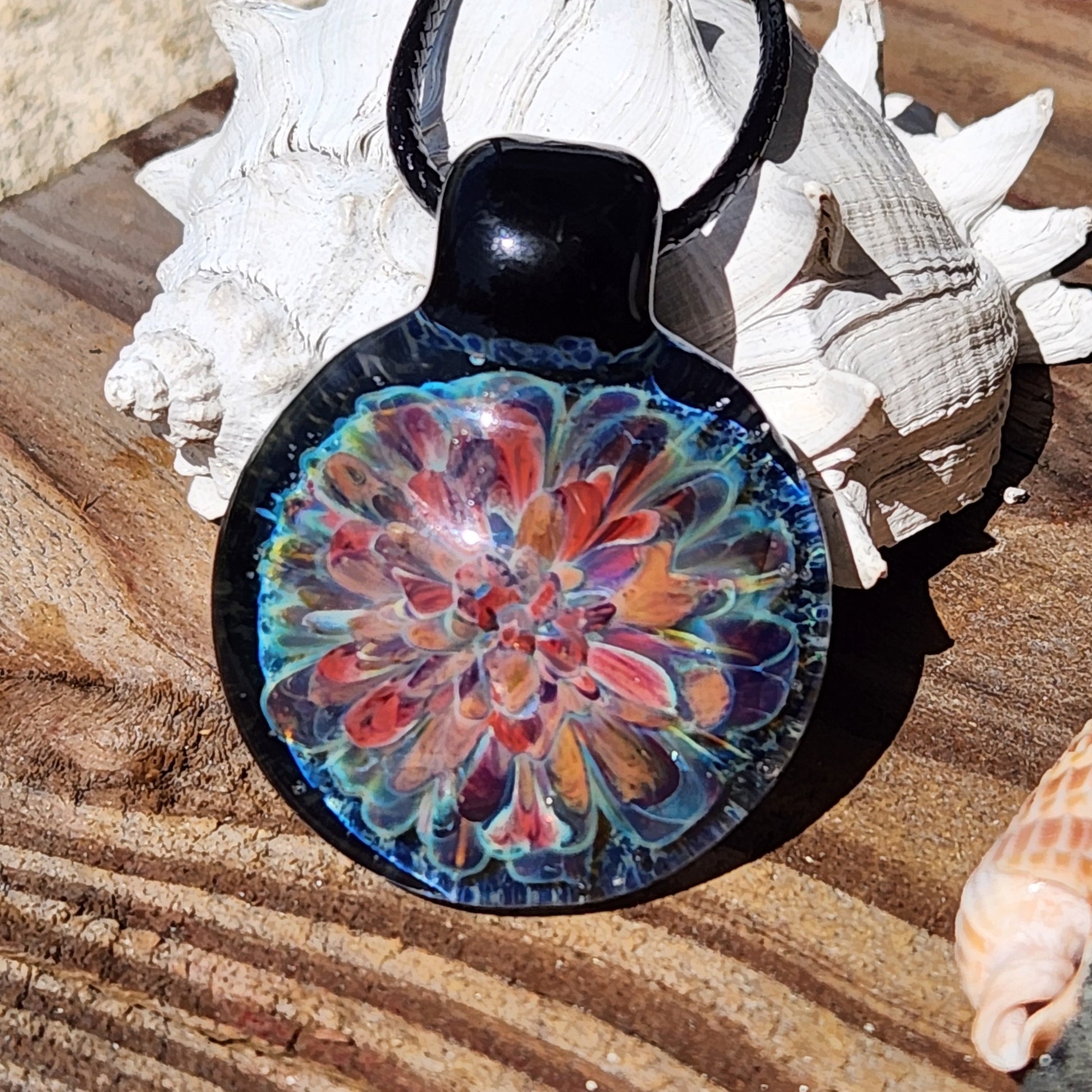 Front view of artisan glass pendant necklace with red, orange, and blue floral pattern. Handmade jewelry gift idea.
