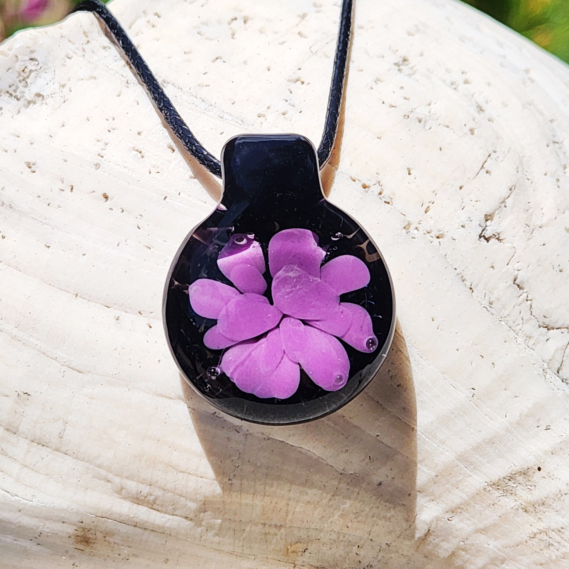 Minimalist purple glass pendant with black background and flower design, handmade in the USA. Lightweight statement necklace for unique gifting.
