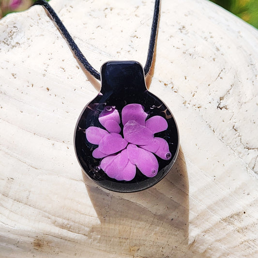 Minimalist purple glass pendant with black background and flower design, handmade in the USA. Lightweight statement necklace for unique gifting.