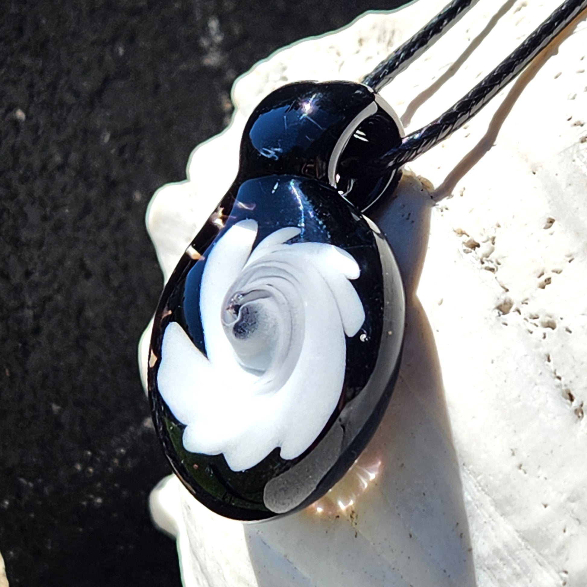 Black and White Swirl Glass Pendant | Handmade Necklace Jewelry Gift displayed on a shell, emphasizing its artistic swirl and high-gloss black base.