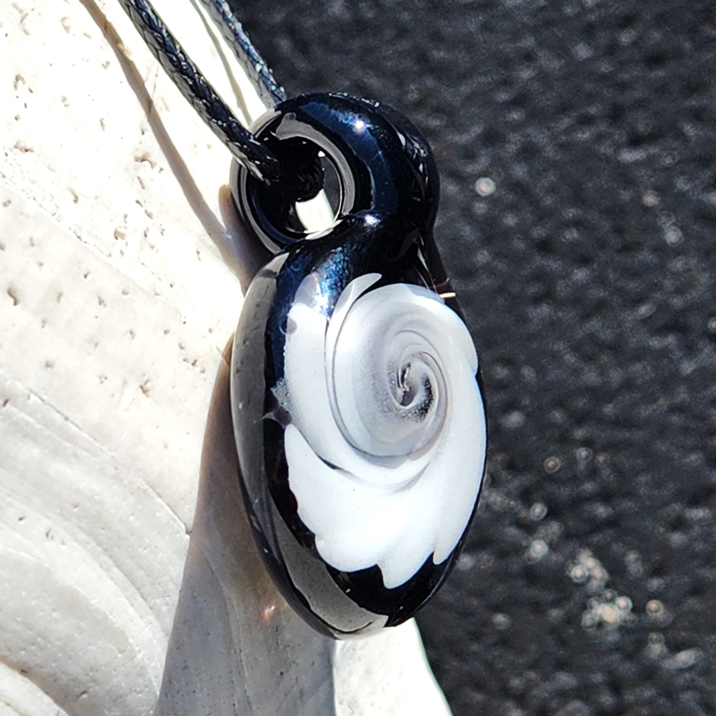 Vertical view of Black and White Swirl Glass Pendant | Handmade Necklace Jewelry Gift hanging on cord, highlighting its glossy black and white swirl.