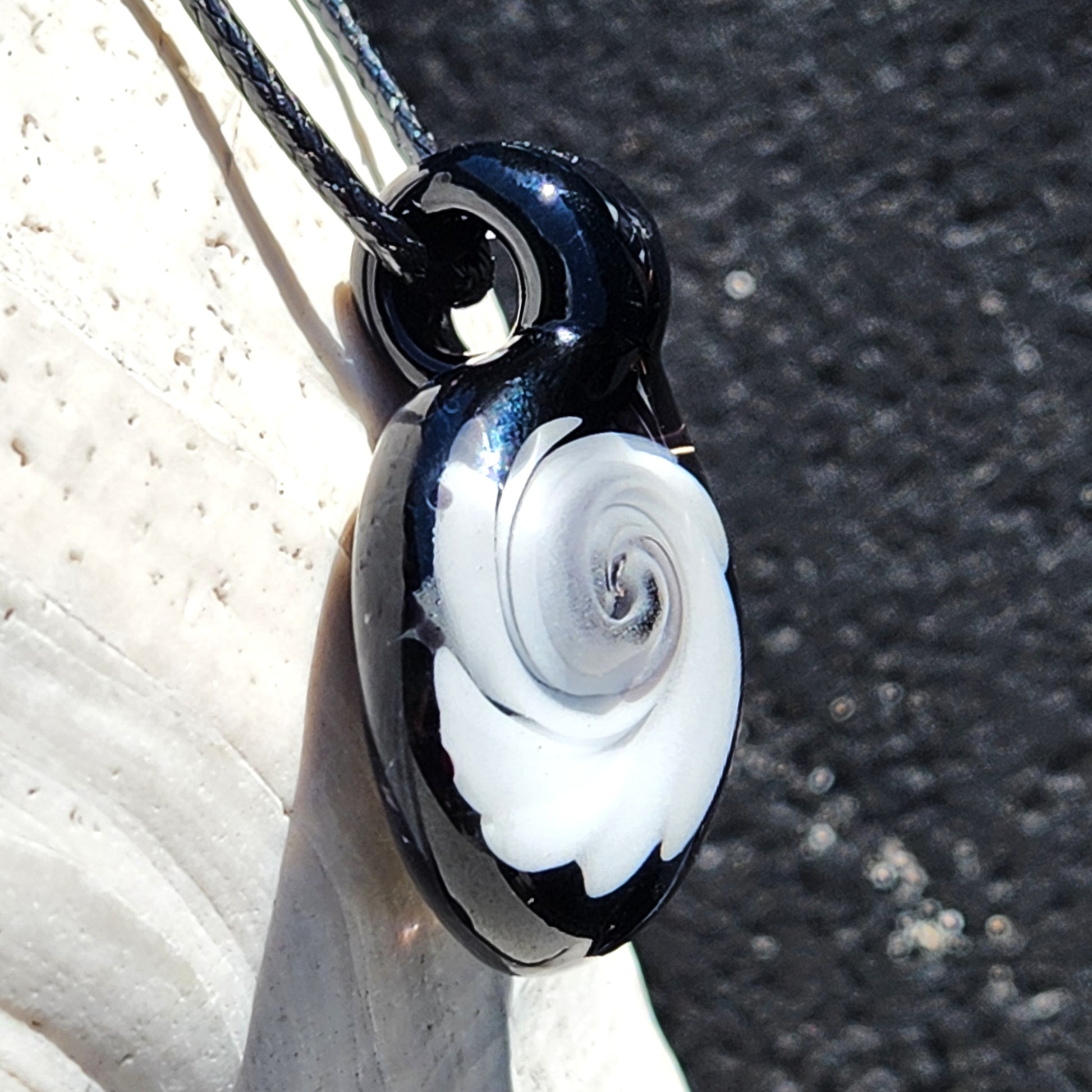 Vertical view of Black and White Swirl Glass Pendant | Handmade Necklace Jewelry Gift hanging on cord, highlighting its glossy black and white swirl.