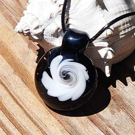 Black and White Swirl Glass Pendant | Handmade Necklace Jewelry Gift shown on wood with seashell, featuring bold swirl design in glossy finish.