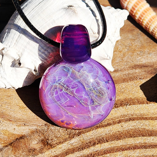 Purple glass pendant necklace with silver and gold fuming, displayed on wood with seashells. Bold artisan jewelry in vivid purple tones.