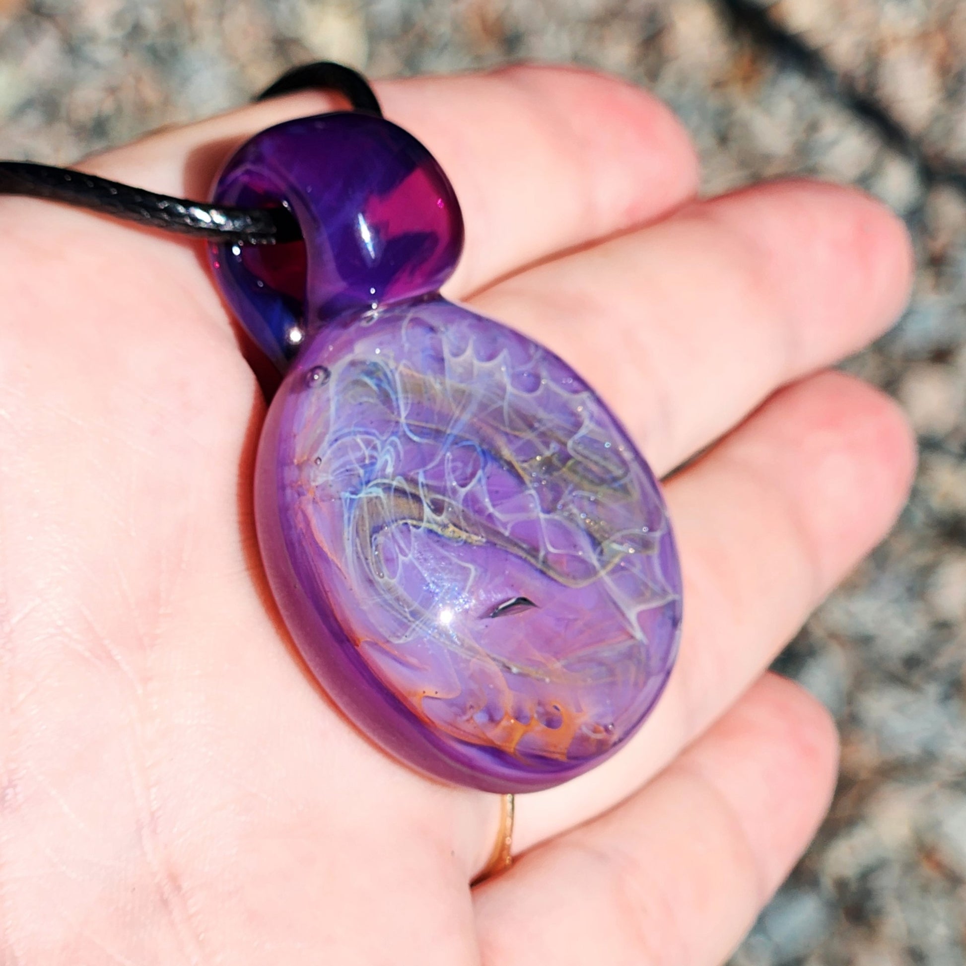 Purple glass pendant necklace shown in hand for scale. Handmade with silver and gold fuming for a vibrant, heady look.