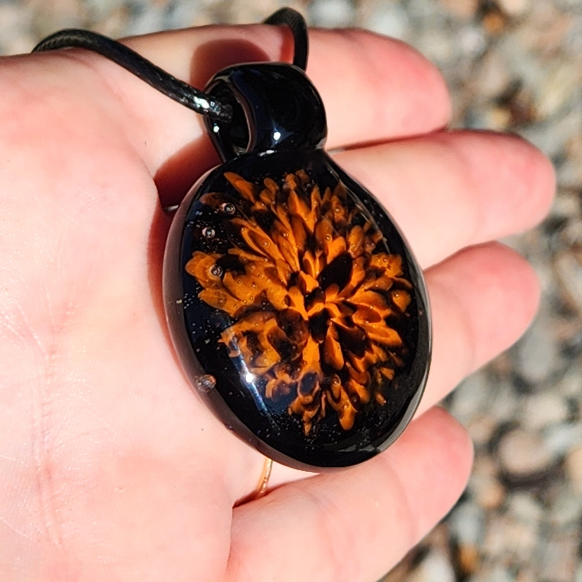 Fiery Glass Pendant Necklace held in hand, emphasizing its size and vivid orange bloom. Handmade fall accessory perfect for Halloween-themed outfits.