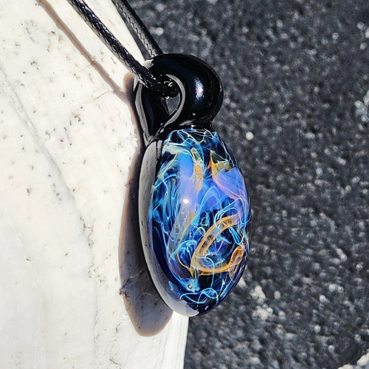 Angled view of Handmade Glass Pendant – Unique Gold & Silver Fumed Black Necklace highlighting colorful fume patterns.