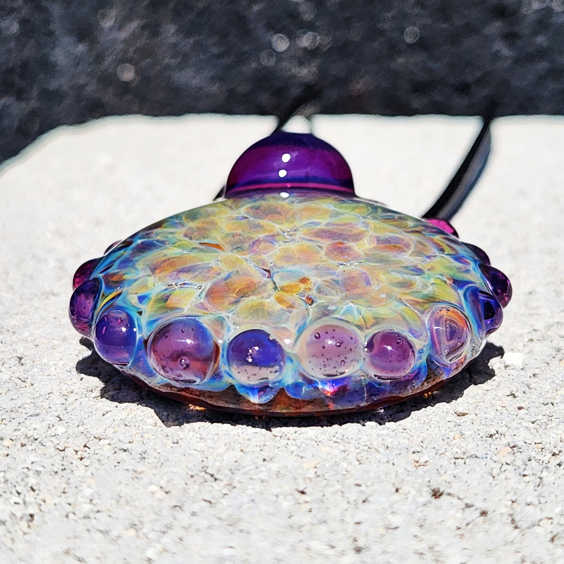 Bottom view of handmade rainbow shimmer pendant with textured purple glass edge. Artistic borosilicate jewelry for bold fashion.
