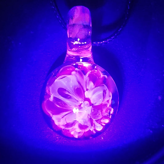 UV Glow Glass Pendant glowing pink under blacklight, showcasing handmade blown glass flower design. Ideal for festivals and unique jewelry lovers.
