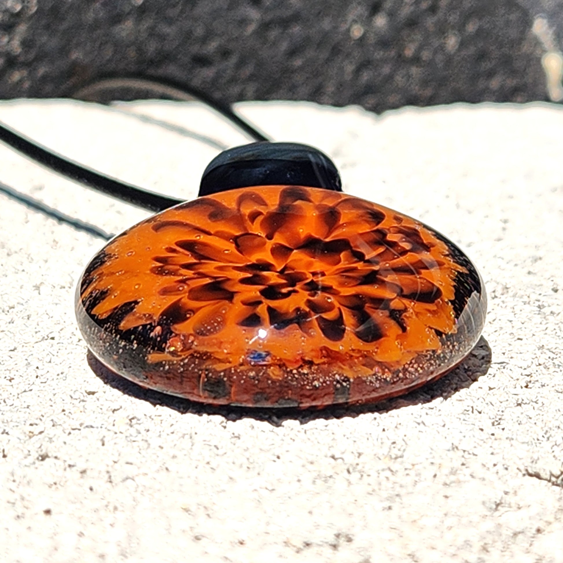 Bottom view of Handmade Fiery Flame Glass Pendant with layered orange and red bloom. Unique fall jewelry with black glass loop.