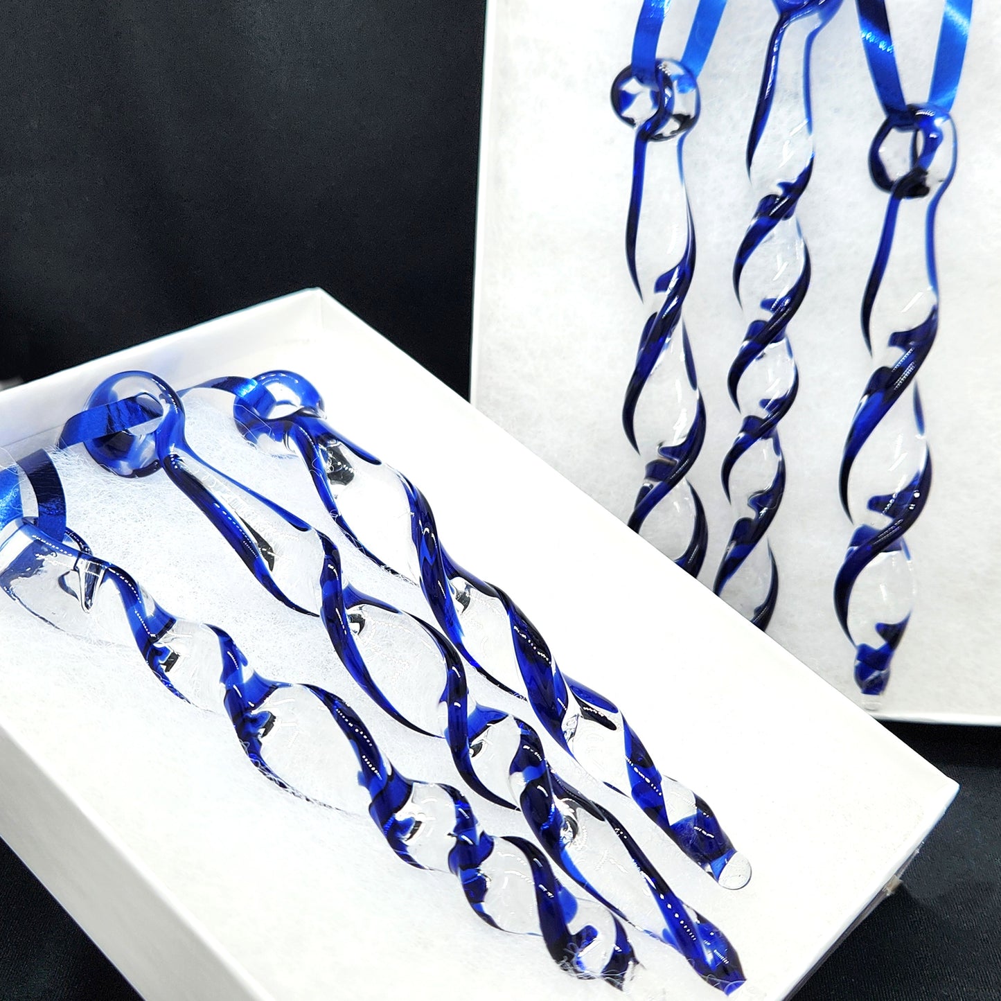 Two sets of handmade blue glass Christmas ornaments in gift boxes. Twisted icicle suncatchers ideal for festive home or garden decoration.