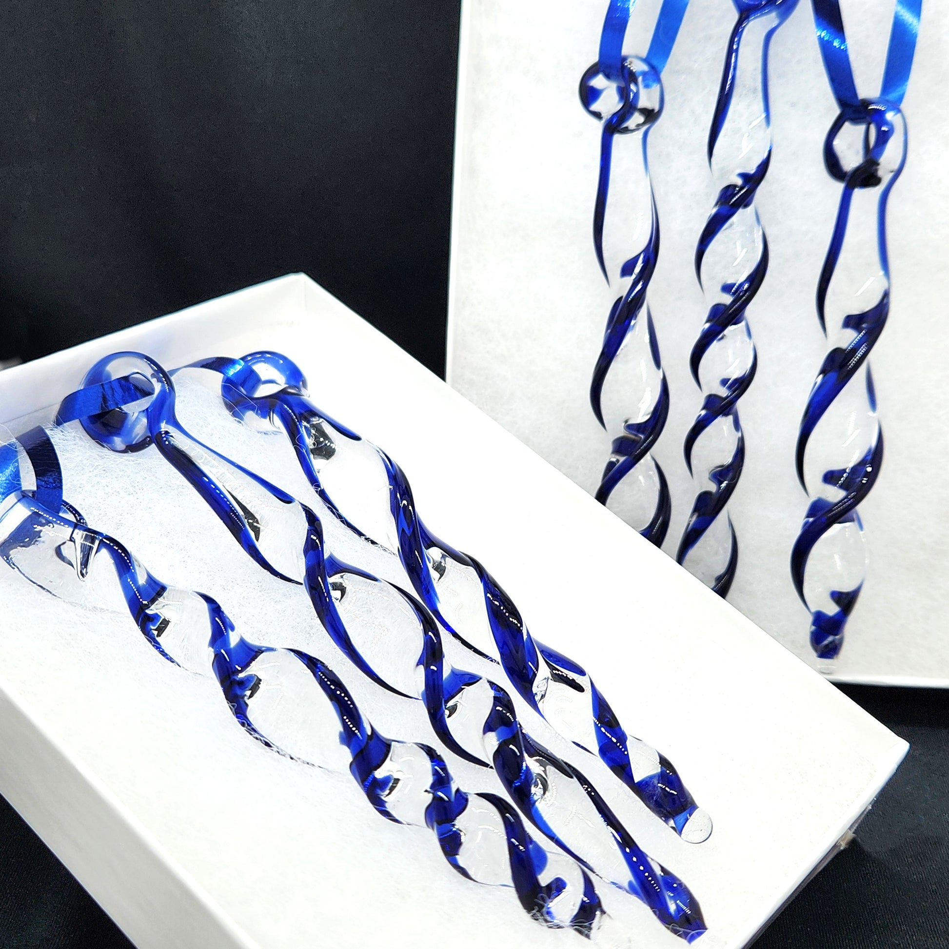 Two sets of handmade blue glass Christmas ornaments in gift boxes. Twisted icicle suncatchers ideal for festive home or garden decoration.