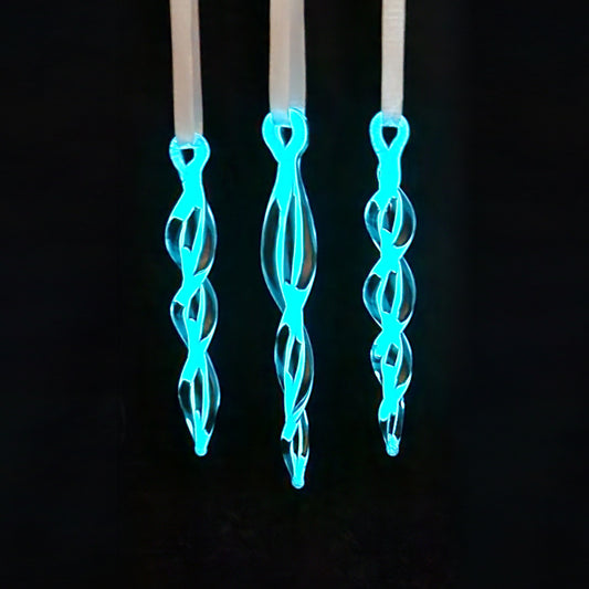 Glow-in-the-dark Christmas tree glass ornaments shaped like twisted icicles with blue luminescence. Unique holiday decor for seasonal tree accents.