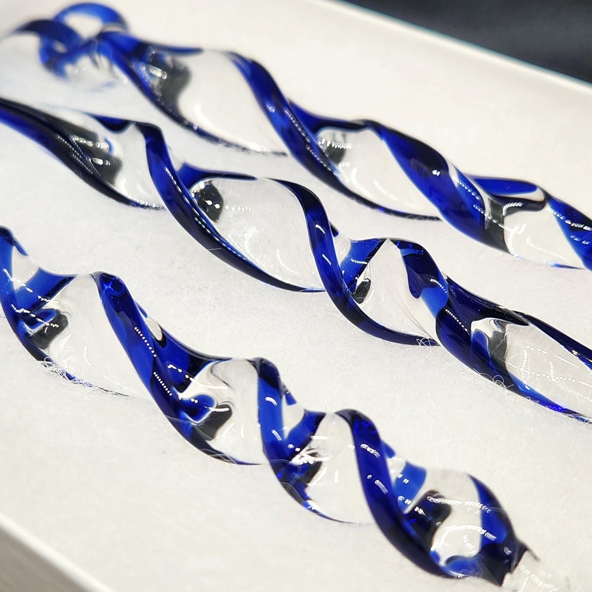 Close-up of handmade blue glass Christmas ornaments showing intricate twisted icicle design. Perfect as suncatchers or festive tree decorations.