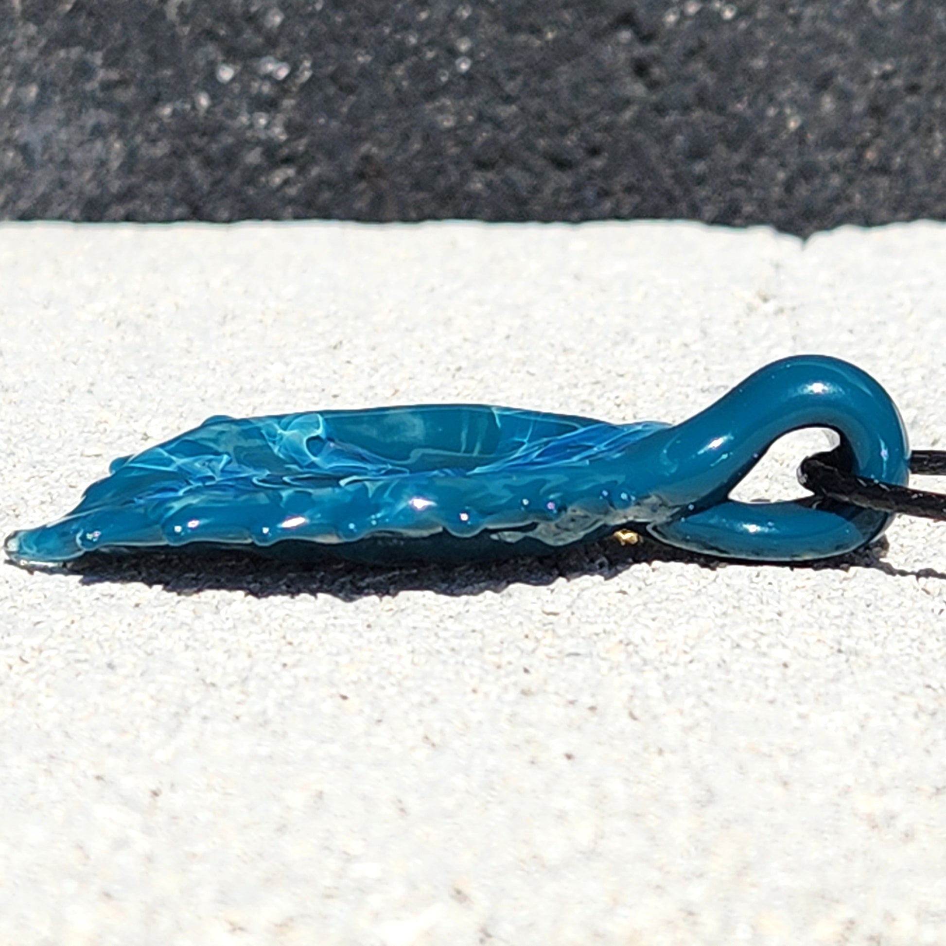 Low profile view of Ocean Drift Glass Pendant Necklace highlighting its smooth glass finish and unique wave-like texture.