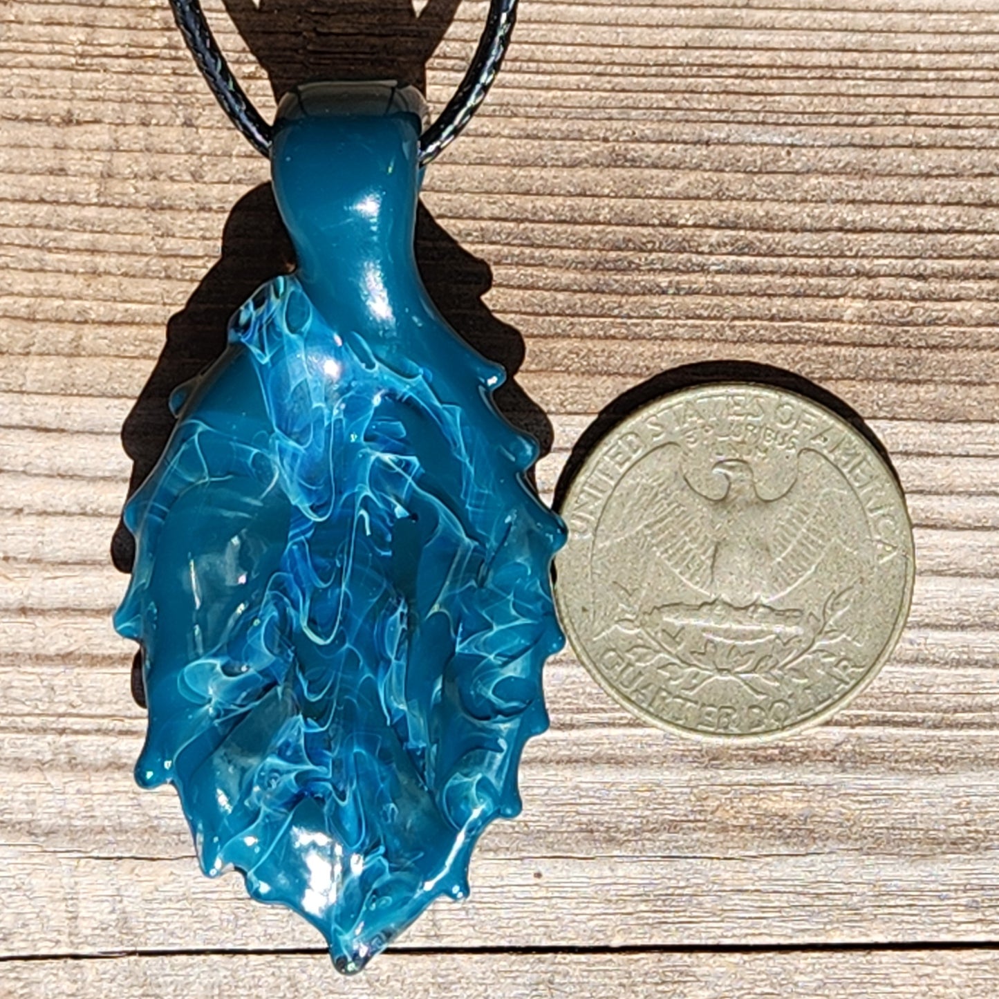 Ocean Drift Glass Pendant Necklace next to a US quarter for size comparison, showcasing its compact and wearable handmade design.