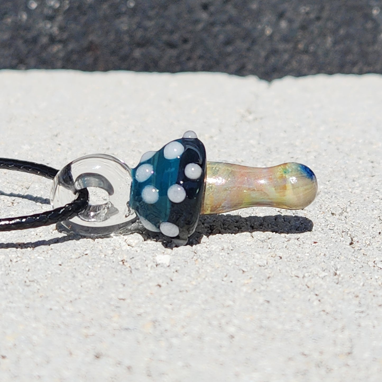 Side view of Blue Mushroom Handmade Glass Pendant with iridescent stem and blue cap, a small artistic necklace for nature lovers.
