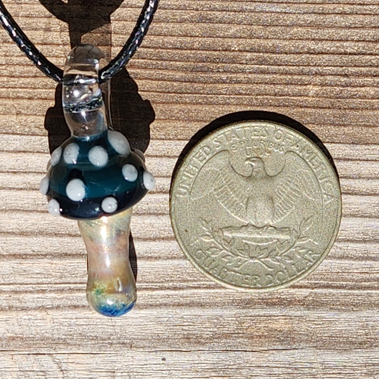 Size comparison of Blue Mushroom Glass Pendant next to a US coin, showing its compact handmade design. Ideal for boho jewelry collections.
