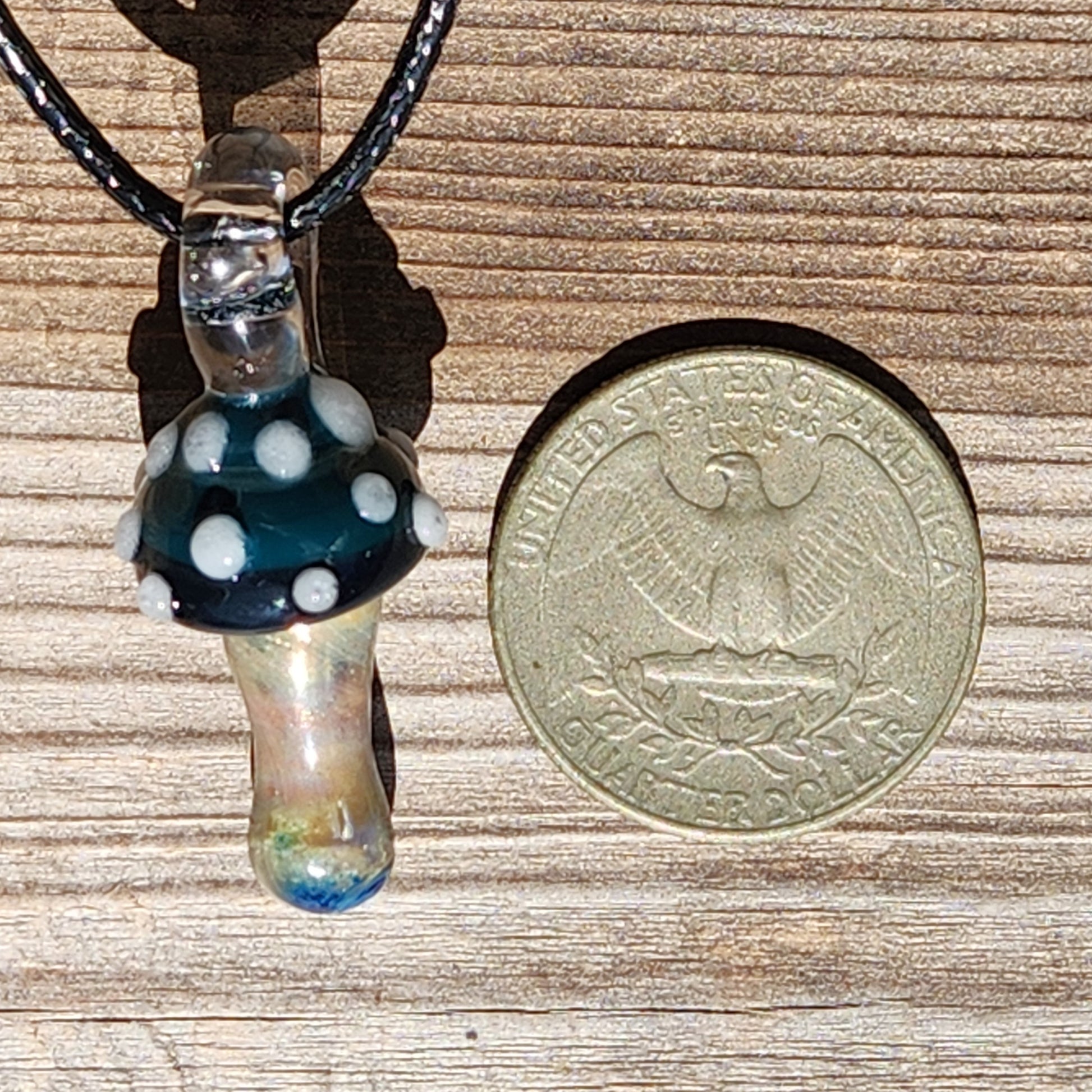 Size comparison of Blue Mushroom Glass Pendant next to a US coin, showing its compact handmade design. Ideal for boho jewelry collections.