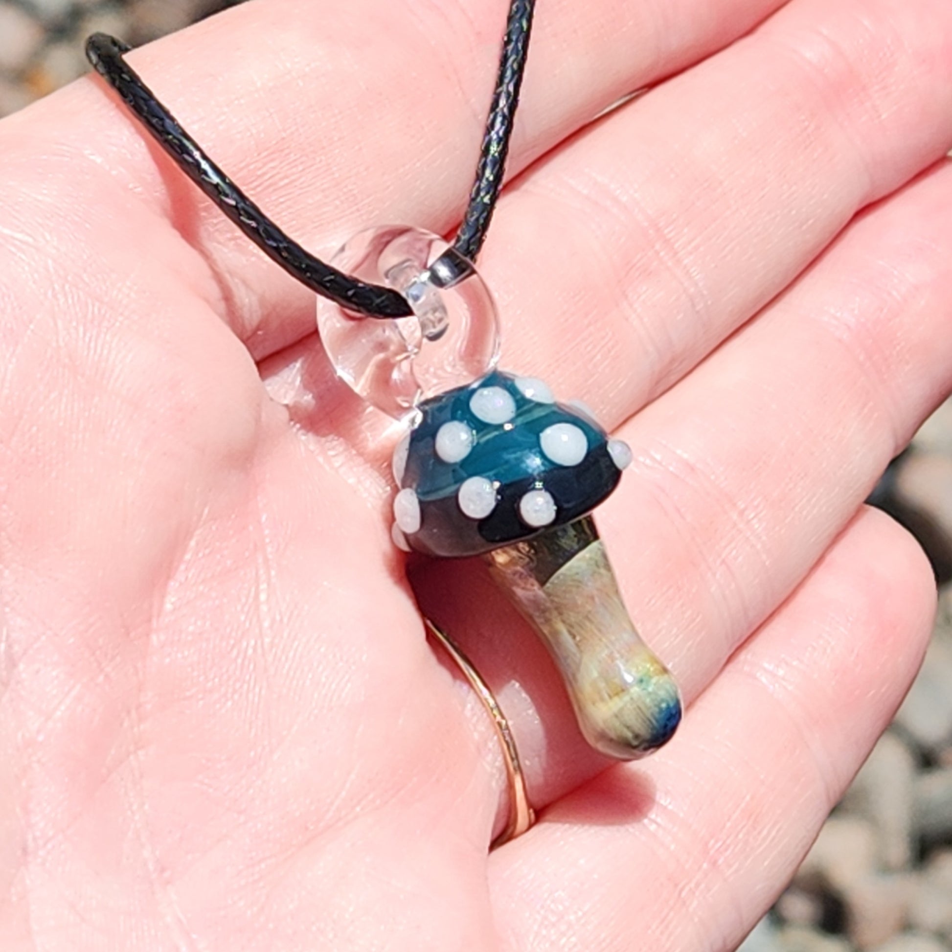 Blue Mushroom Pendant Necklace displayed in hand, showing its small size and intricate glasswork. A perfect handmade gift for art lovers.
