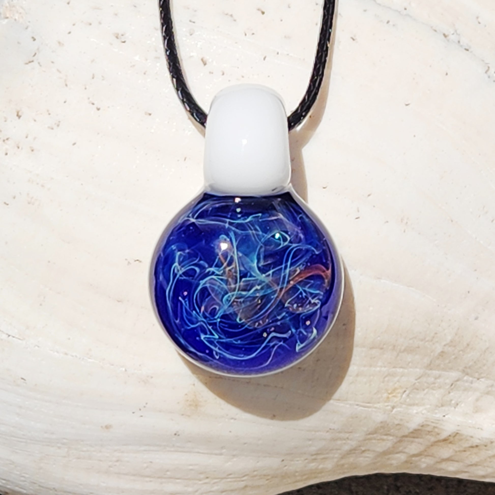 Handmade Deep Blue Galaxy Pendant Necklace with silver and gold fuming, shown against a white seashell for contrast.