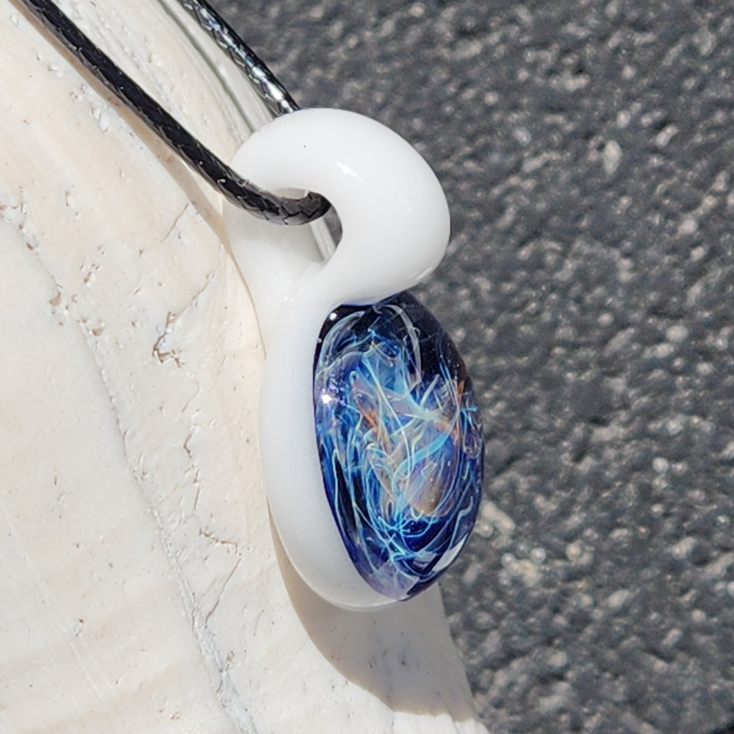 Side angle of Deep Blue Galaxy Pendant Necklace with white glass loop and vibrant swirling core, ideal for artisan jewelry collections.
