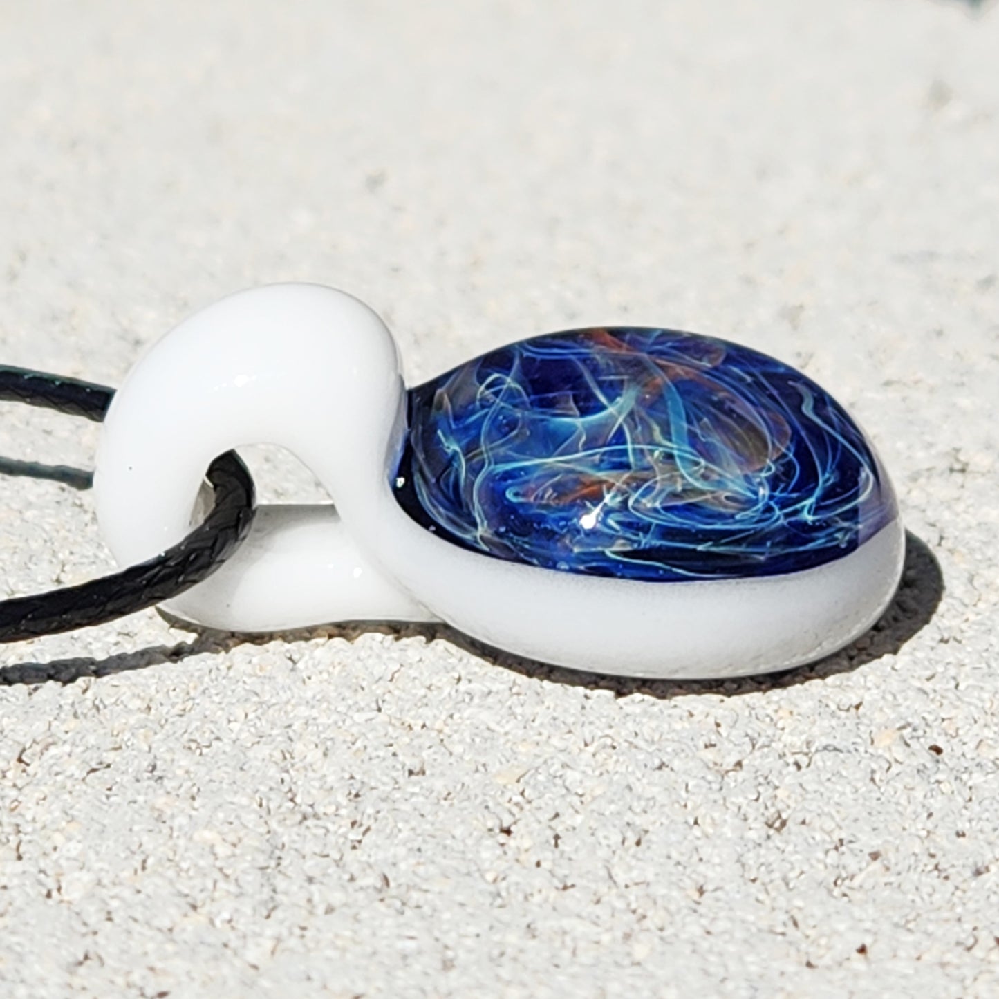 Side view of Deep Blue Galaxy Pendant Necklace showing domed glass surface with intricate swirls, handmade and gift-ready.