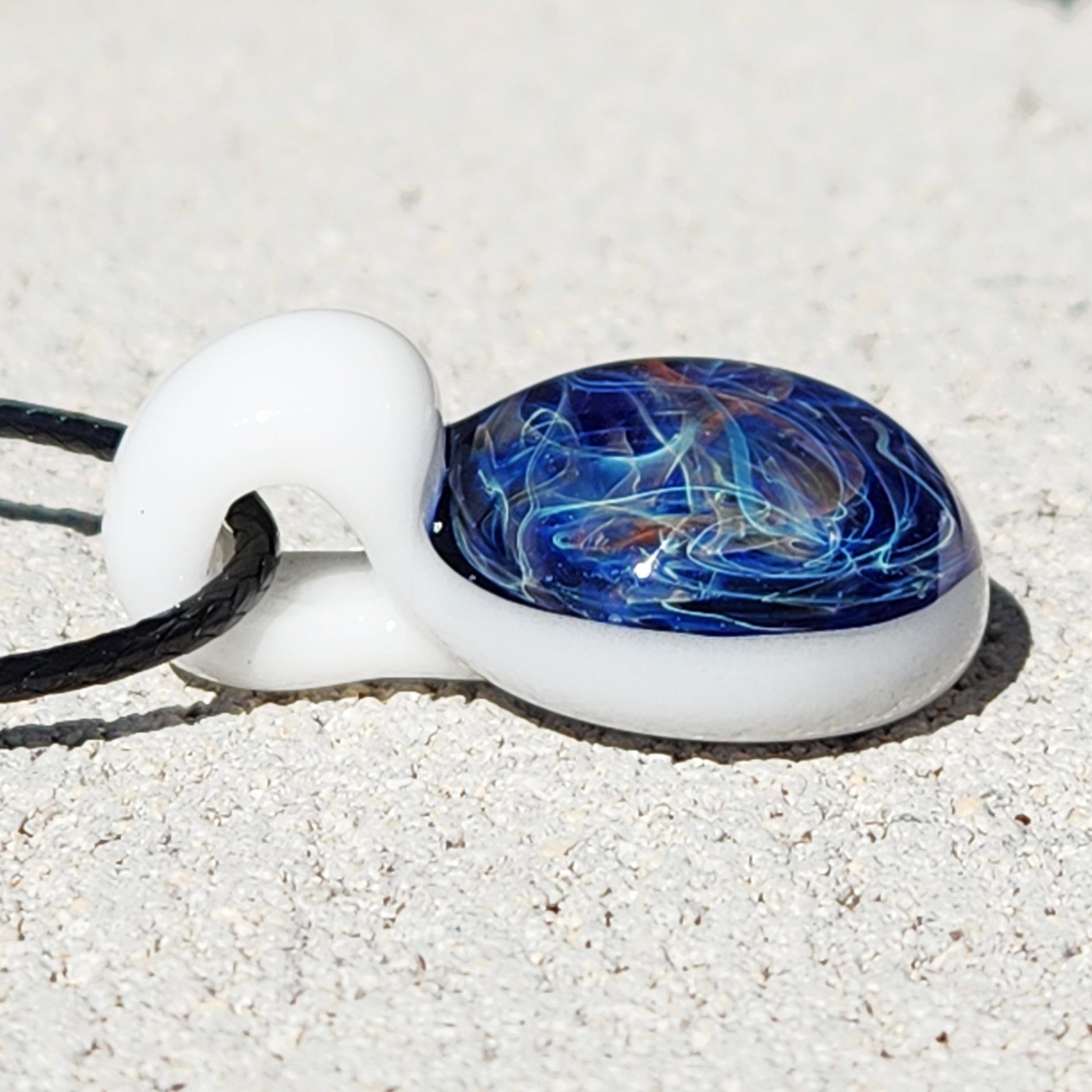 Side view of Deep Blue Galaxy Pendant Necklace showing domed glass surface with intricate swirls, handmade and gift-ready.