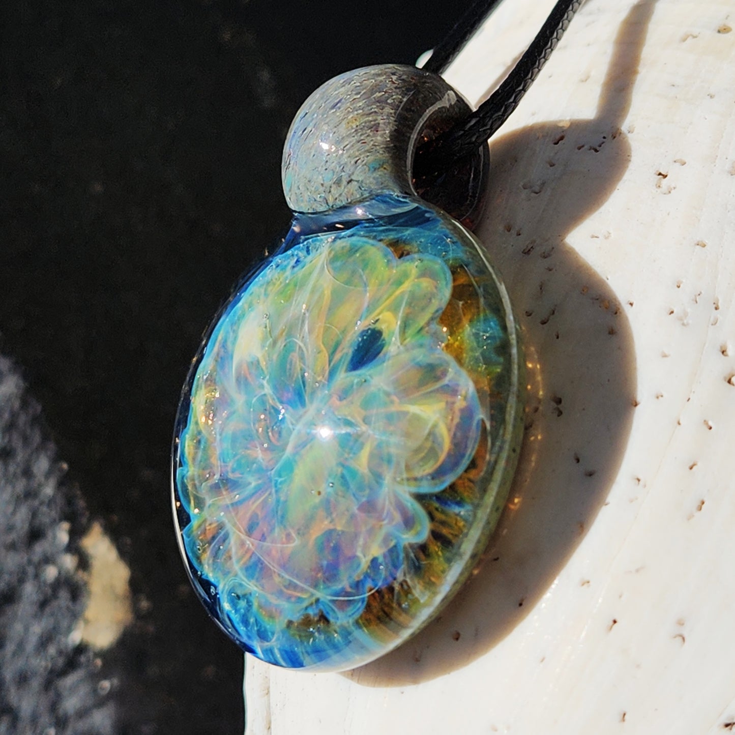 Close-up of Handmade Glass Pendant Necklace with ocean wave pattern and shimmering colors. Unique and artistic jewelry accessory.