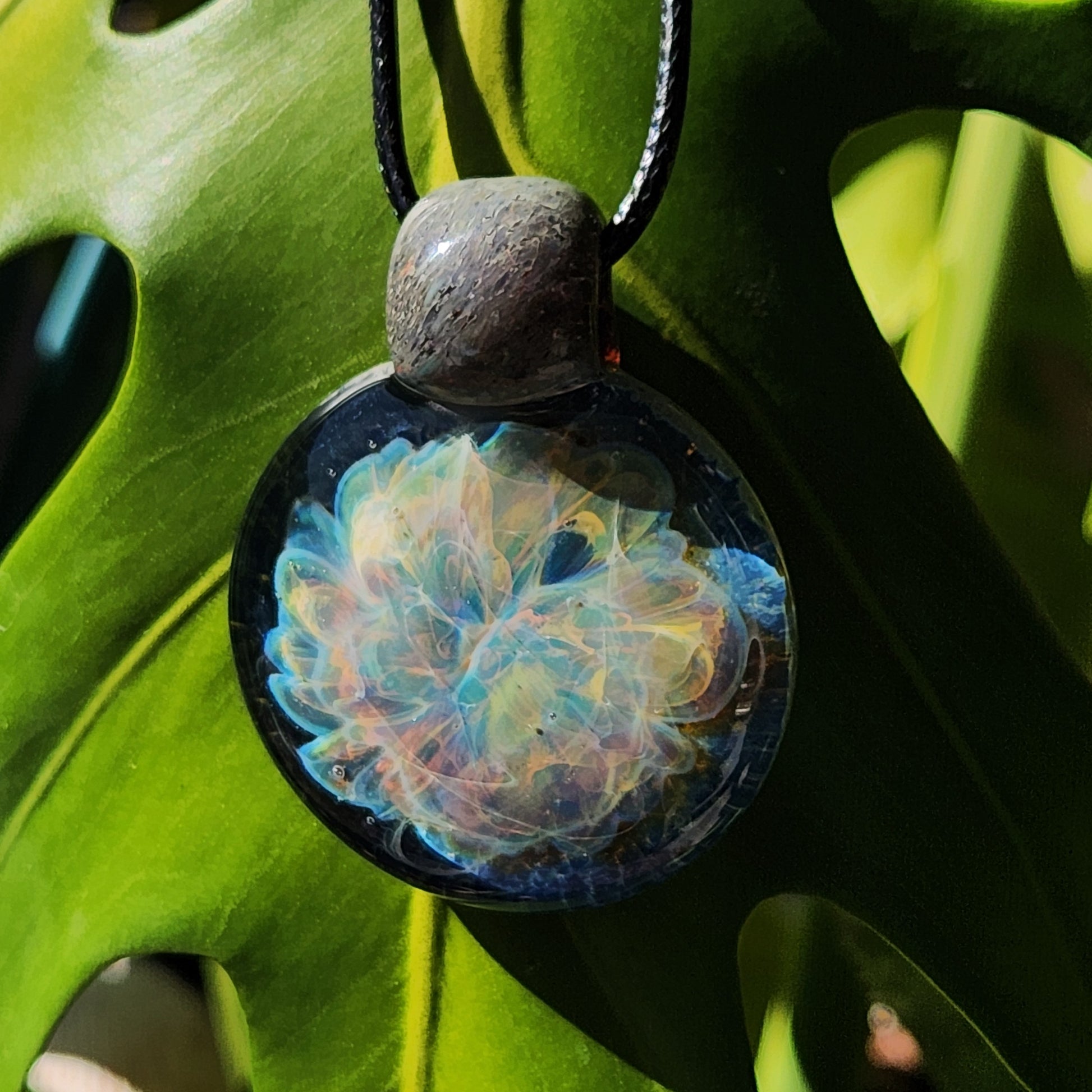 Handmade Glass Pendant Necklace with swirling ocean colors, hanging on a black cord. One-of-a-kind artisan jewelry piece.