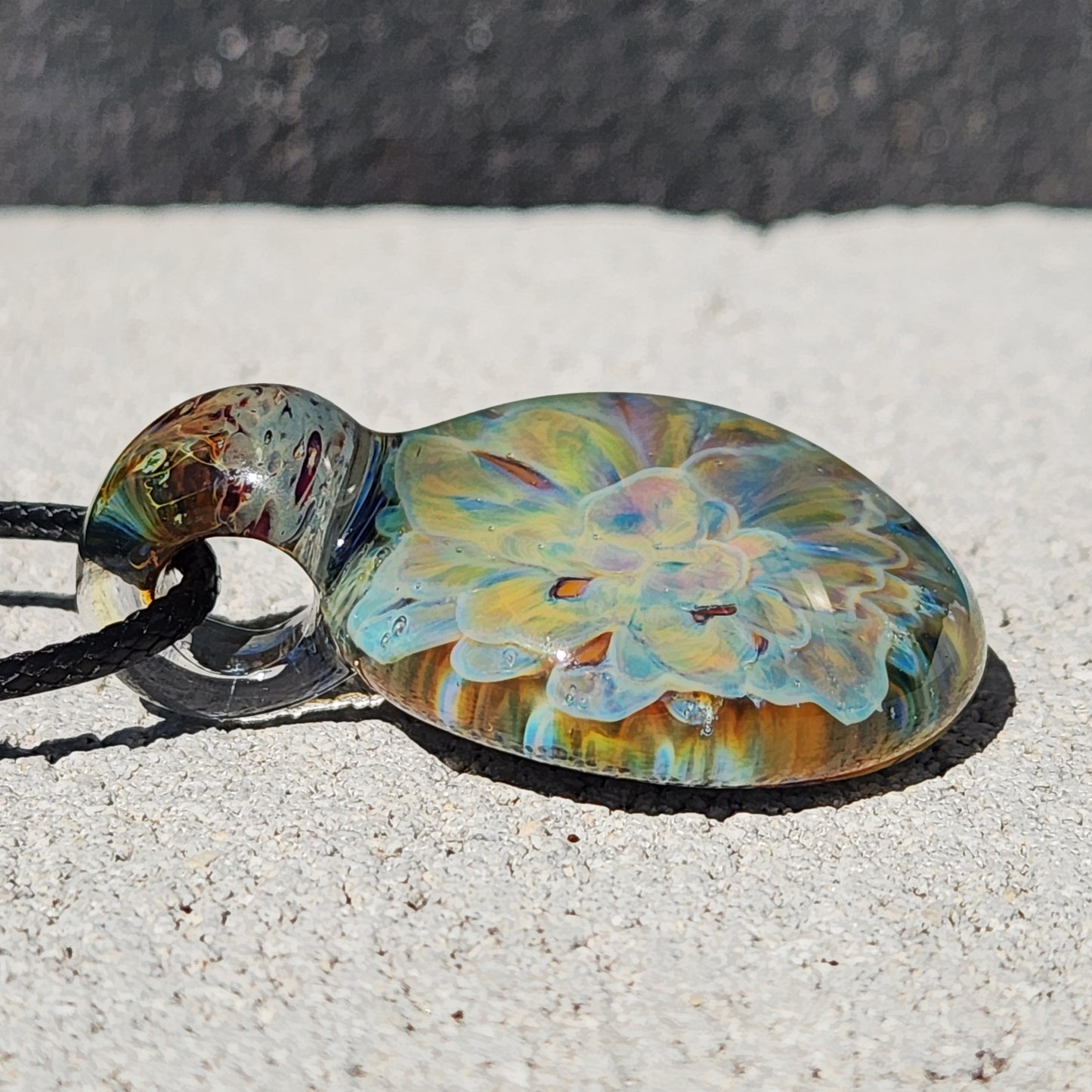 Flat angle of the handmade glass pendant necklace showing detailed yellow and blue floral art with a smooth, rounded finish.