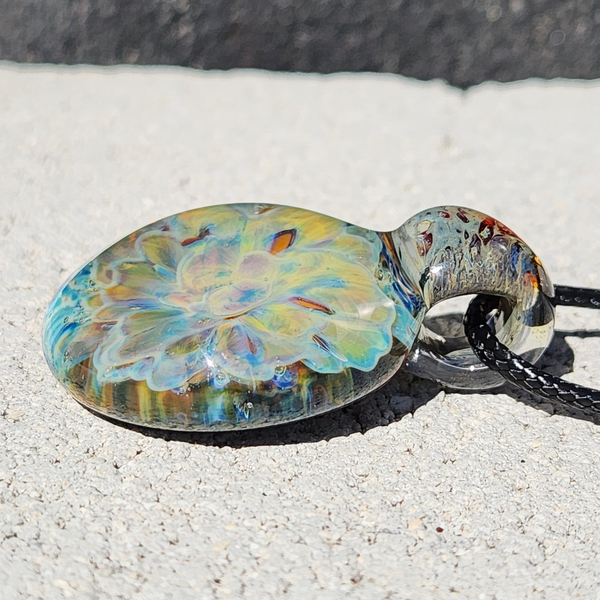 Side profile of the handmade glass pendant necklace showing the layered yellow-blue flower design and clear glass loop.