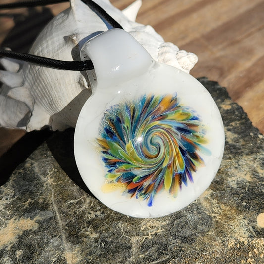 Handmade Spiral Glass Pendant with multicolor swirl on white background, displayed on a rock with seashell. Unique blown glass jewelry gift.