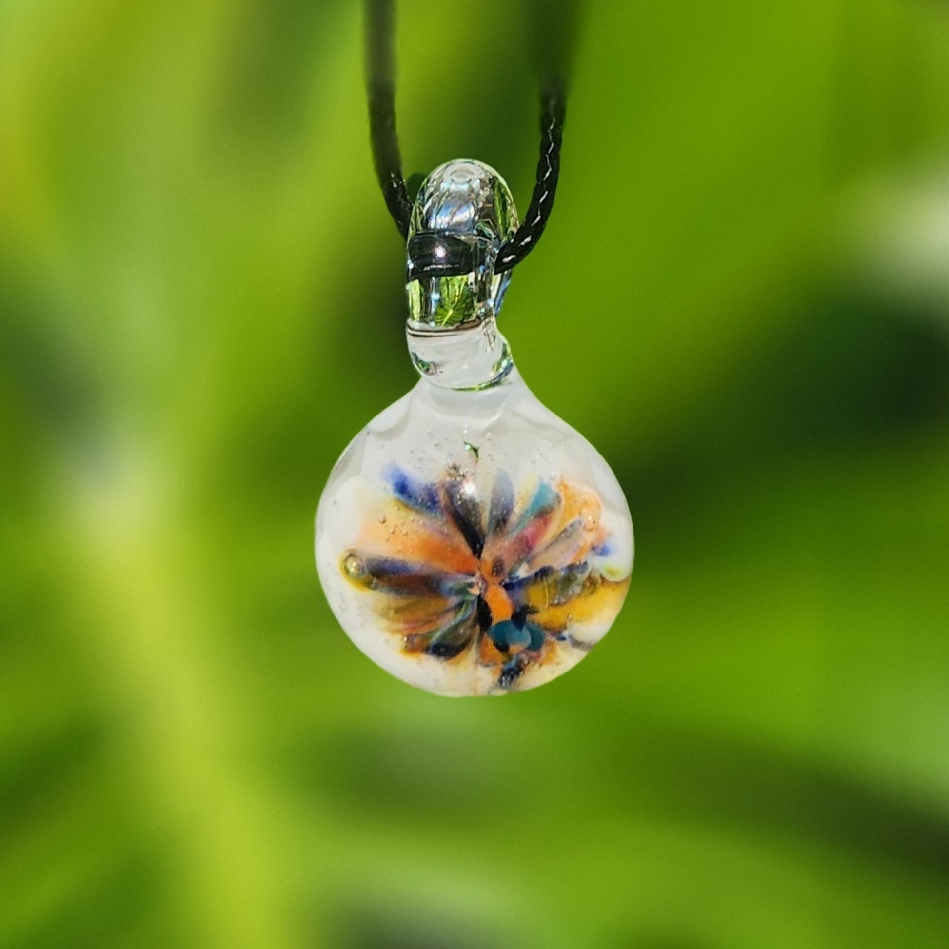Colorful handmade glass pendant with floral rainbow design, suspended on a black cord. Unique borosilicate jewelry for boho fashion lovers.