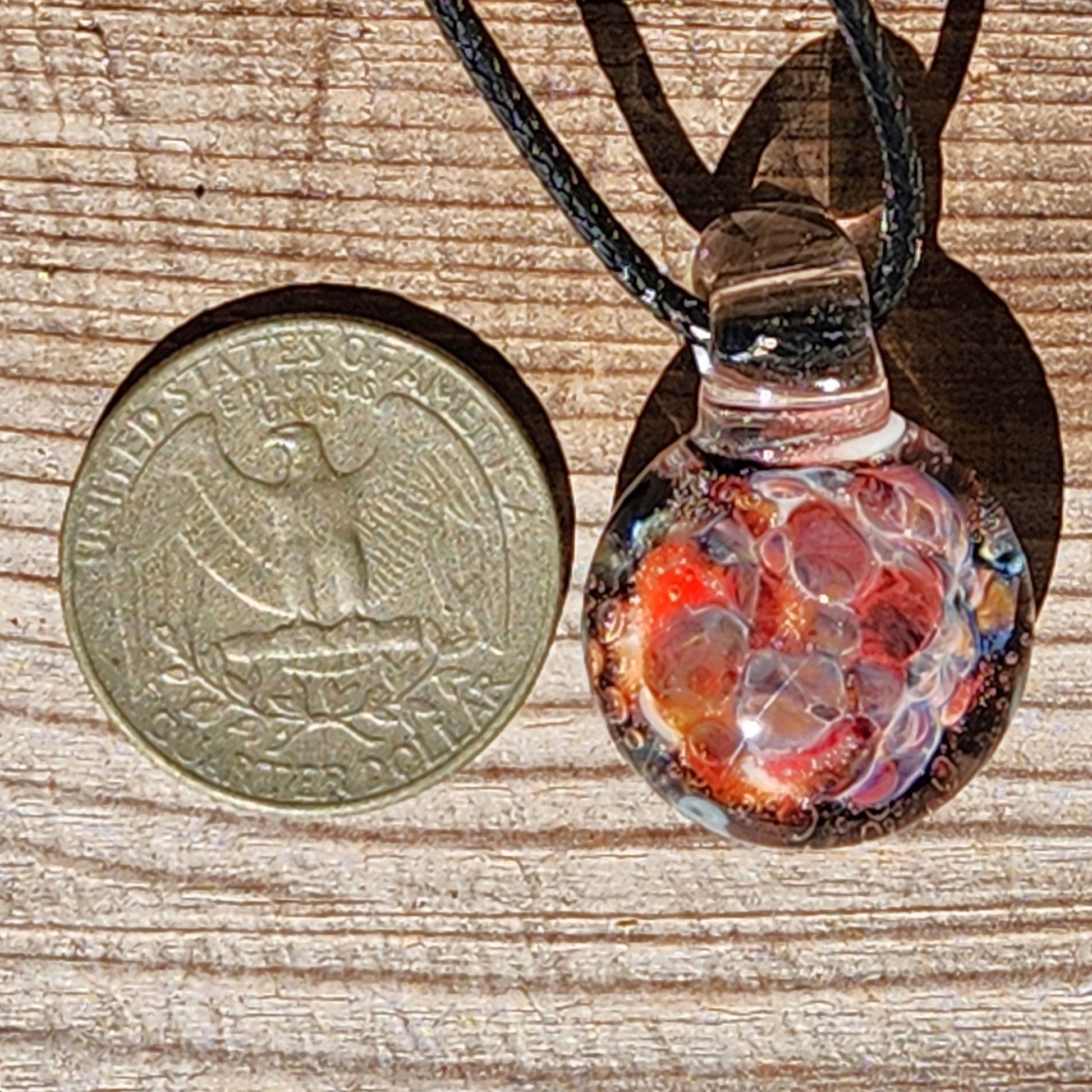Size comparison of handmade glass pendant next to a US quarter, showing its compact and lightweight design.