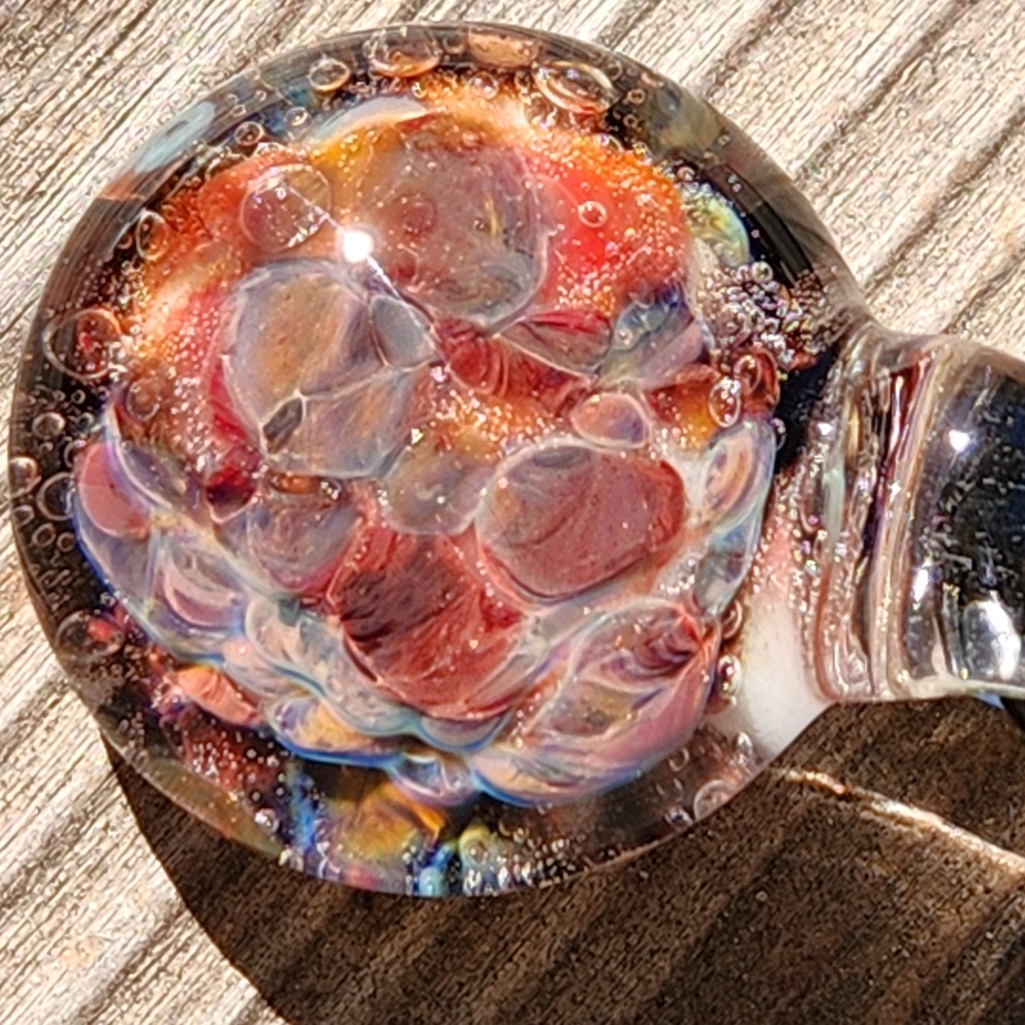 Macro shot of red and multicolor borosilicate glass pendant, emphasizing the intricate bubble and swirl details.