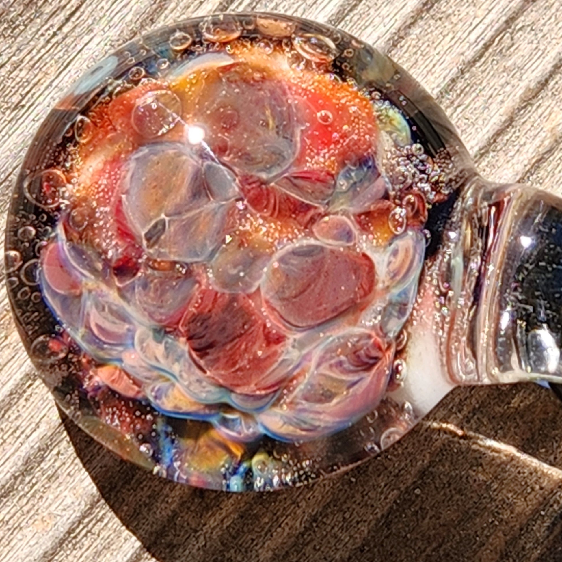 Macro shot of red and multicolor borosilicate glass pendant, emphasizing the intricate bubble and swirl details.
