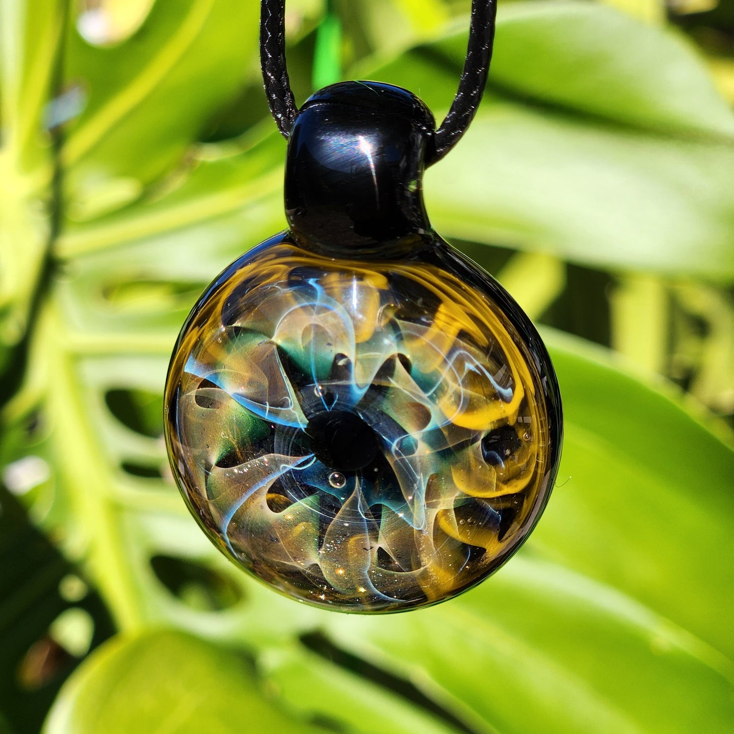 Unique handmade blown glass pendant necklace featuring a swirling galaxy design in black, blue, and gold. A perfect glass jewelry gift for space lovers.