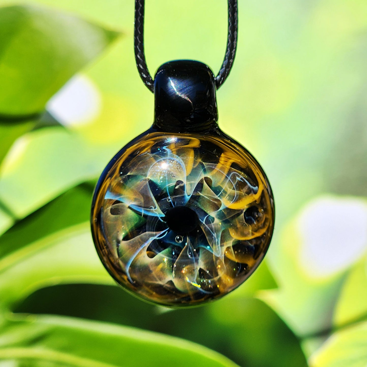 Unique handmade blown glass pendant necklace featuring a swirling galaxy design in black, blue, and gold. A perfect glass jewelry gift for space lovers.