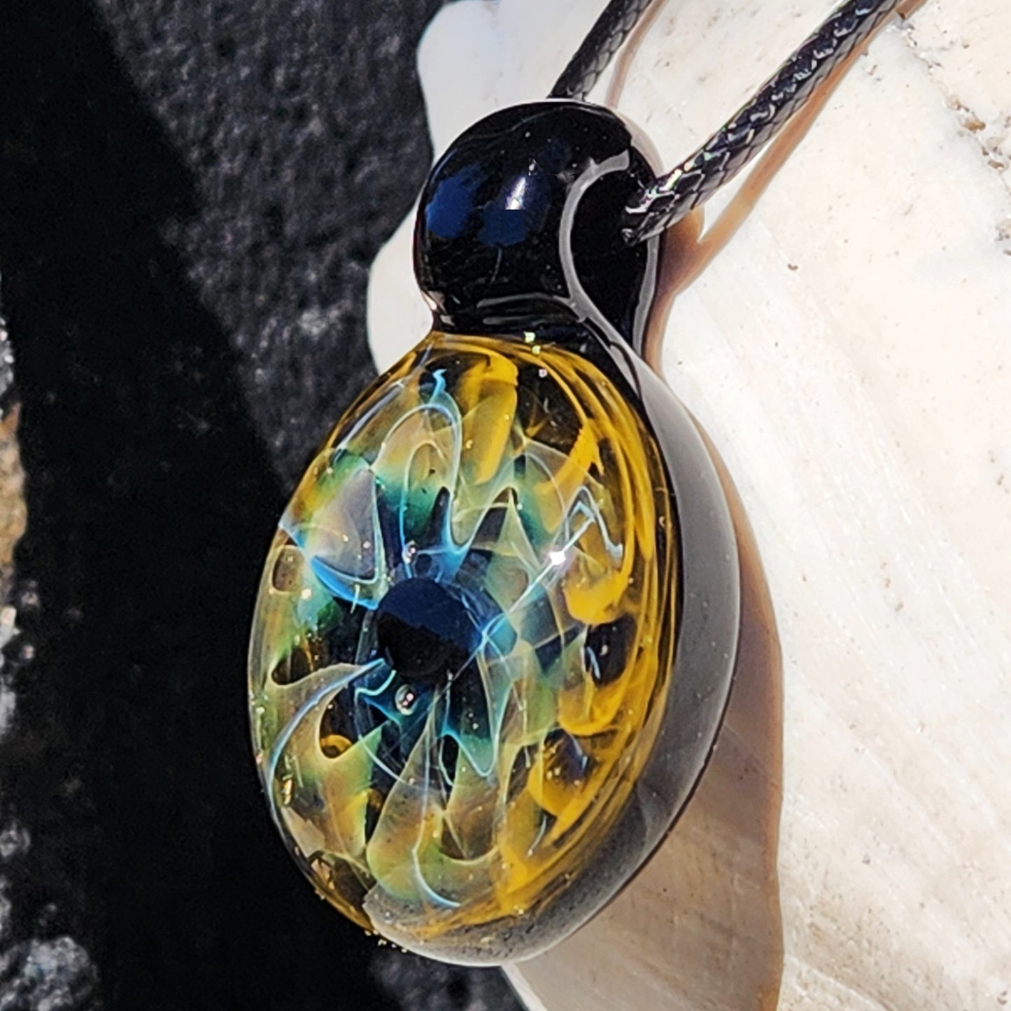 Unique handmade blown glass pendant necklace with swirling galaxy design in black, blue, and gold tones. A perfect glass jewelry gift for space lovers.