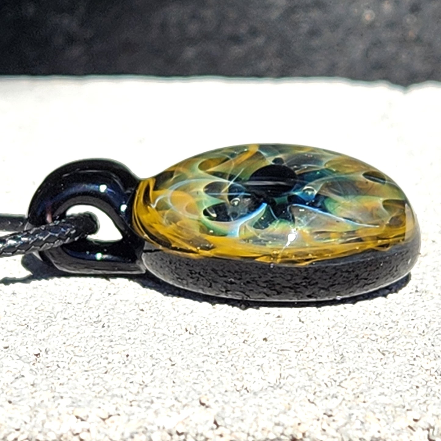 Unique handmade blown glass pendant necklace with swirling galaxy design in black, blue, and gold. A perfect glass jewelry gift for space lovers.