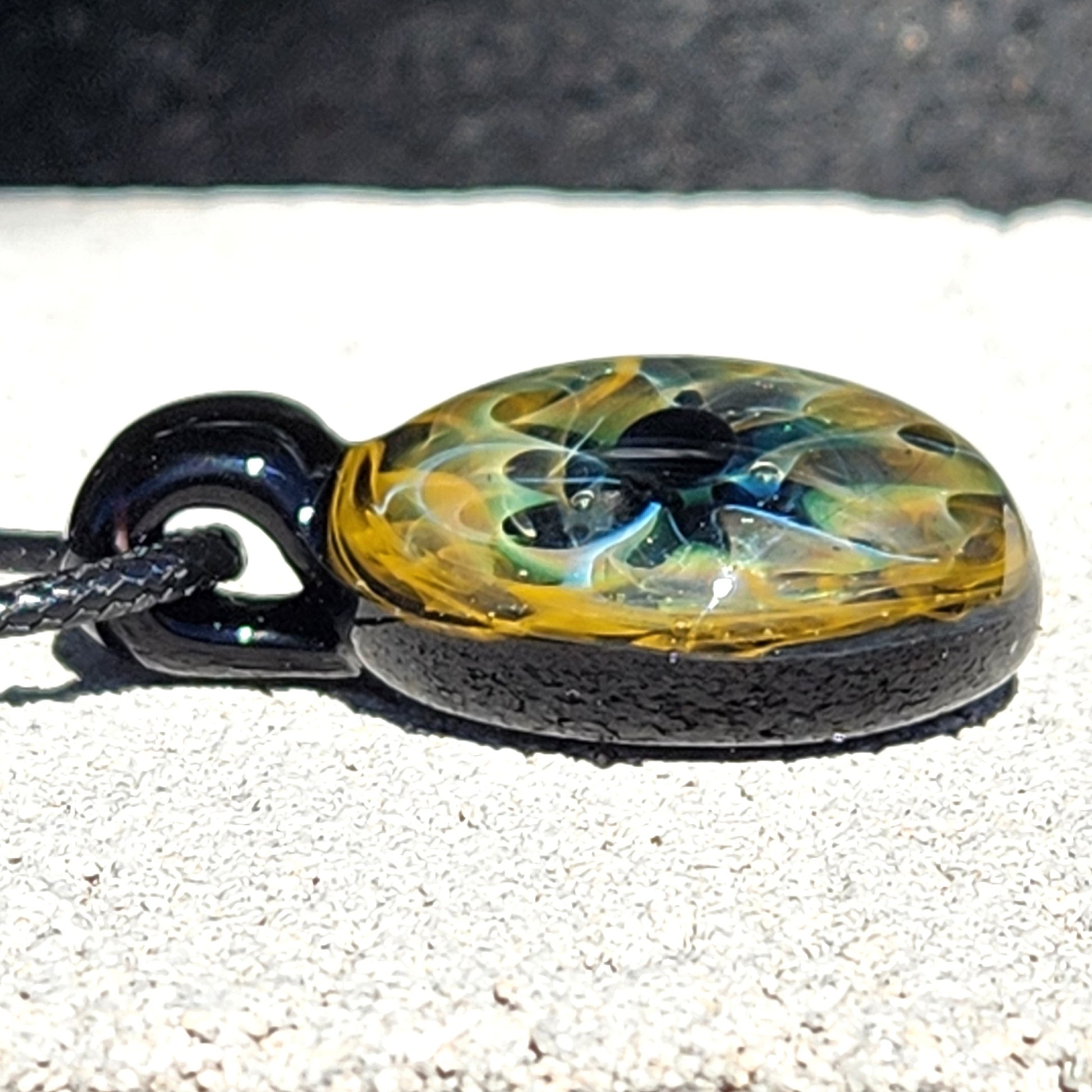 Unique handmade blown glass pendant necklace with swirling galaxy design in black, blue, and gold. A perfect glass jewelry gift for space lovers.