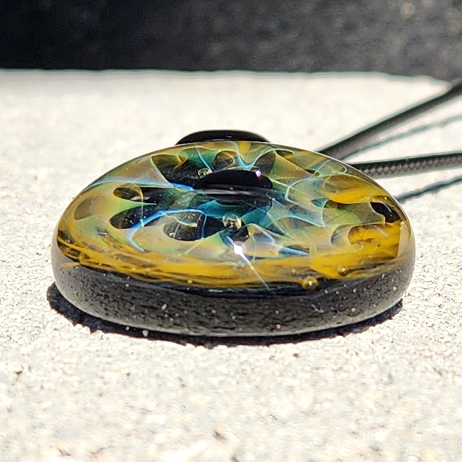 Unique handmade blown glass pendant necklace featuring swirling black, blue, and gold galaxy-inspired design. Ideal glass jewelry gift for space lovers.