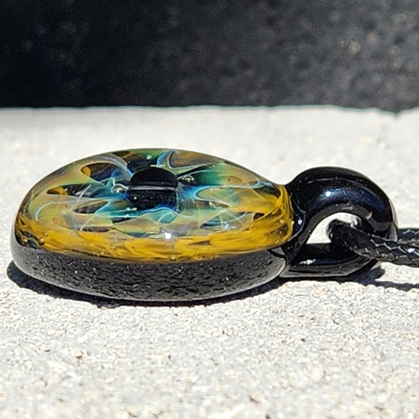 Unique handmade blown glass pendant necklace with swirling black, blue, and gold galaxy design. A perfect glass jewelry gift for space lovers.
