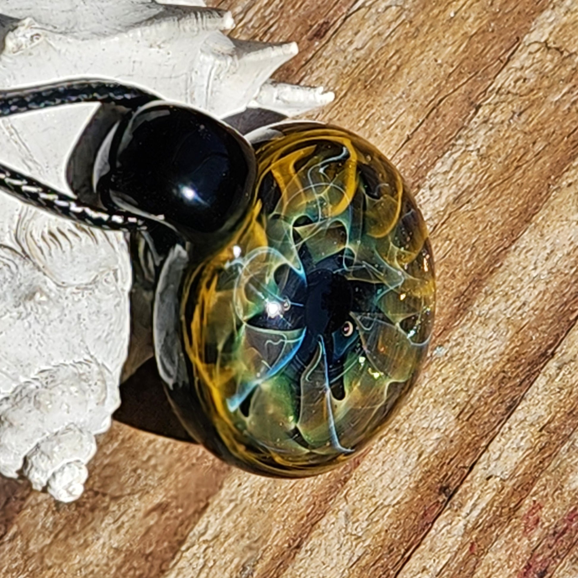 Unique handmade blown glass pendant necklace with swirling galaxy design in black, blue, and gold tones. A perfect glass jewelry gift for space lovers.