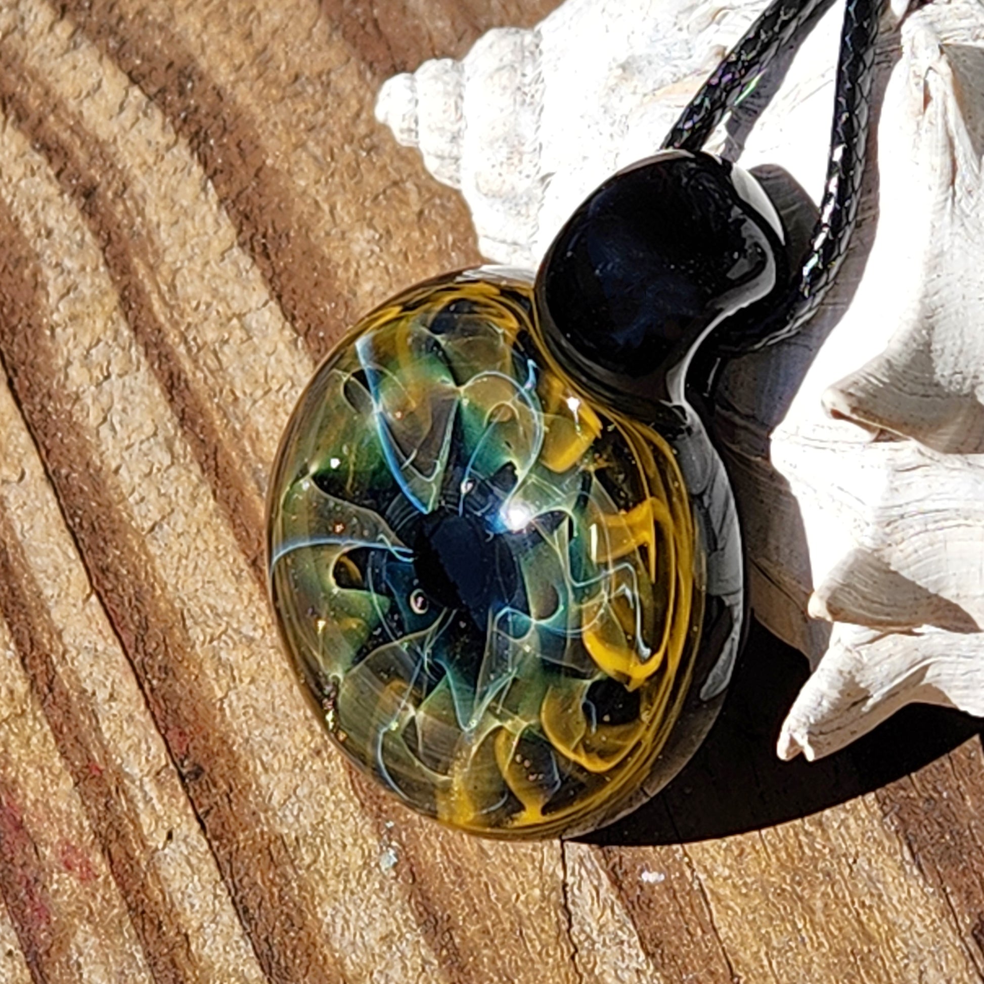 Unique handmade blown glass pendant necklace featuring swirling galaxy-inspired design in black, blue, and gold. Ideal glass jewelry gift for space lovers.