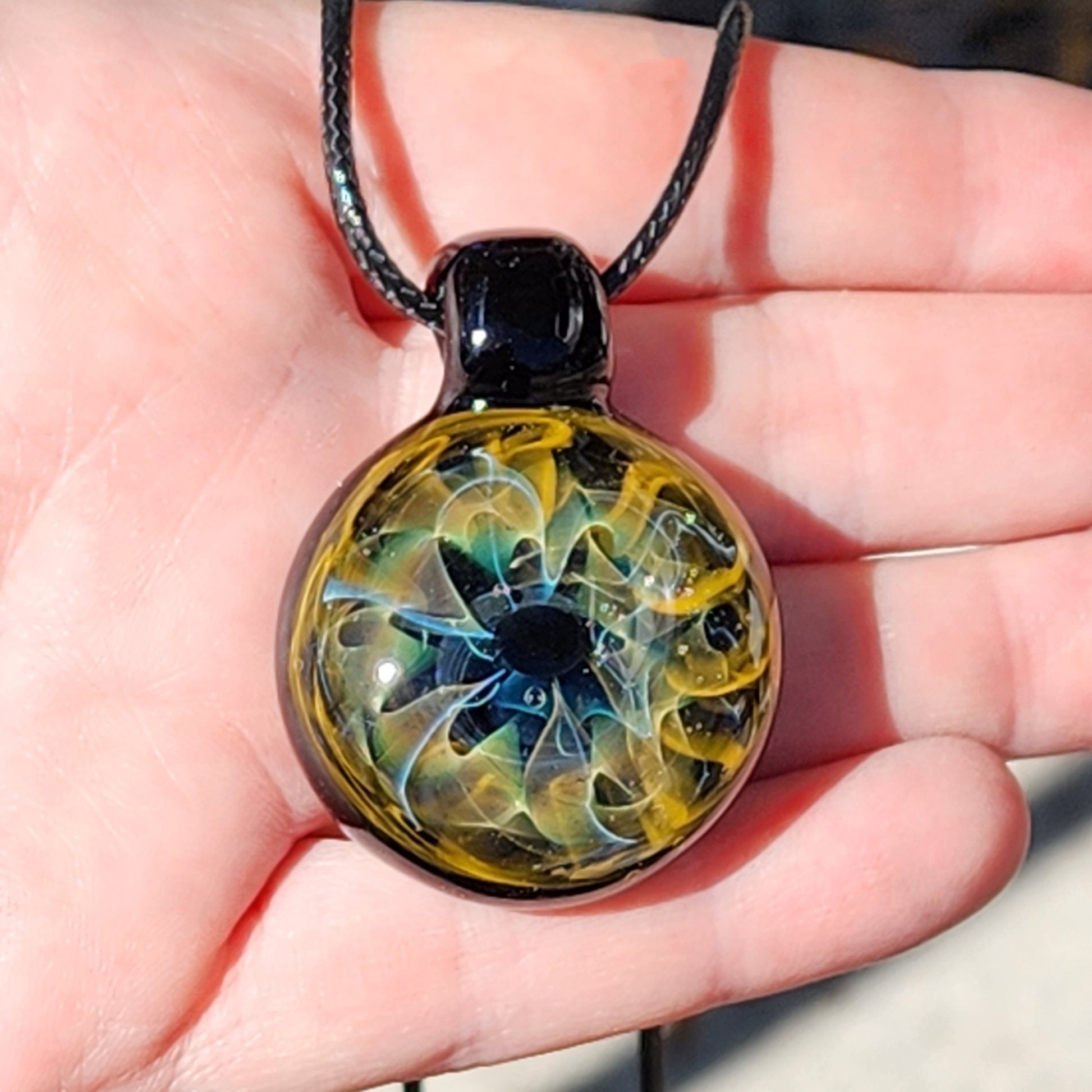 Unique handmade blown glass pendant necklace featuring a swirling galaxy design in black, blue, and gold. A perfect glass jewelry gift for space lovers.